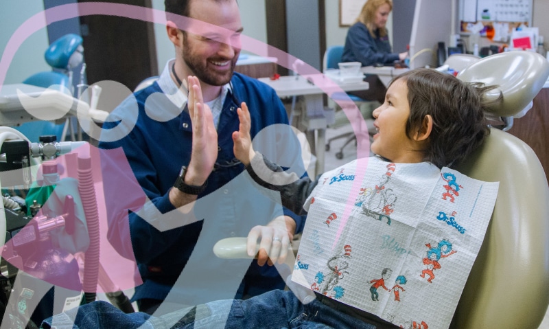 team member talking with young patient in chair
