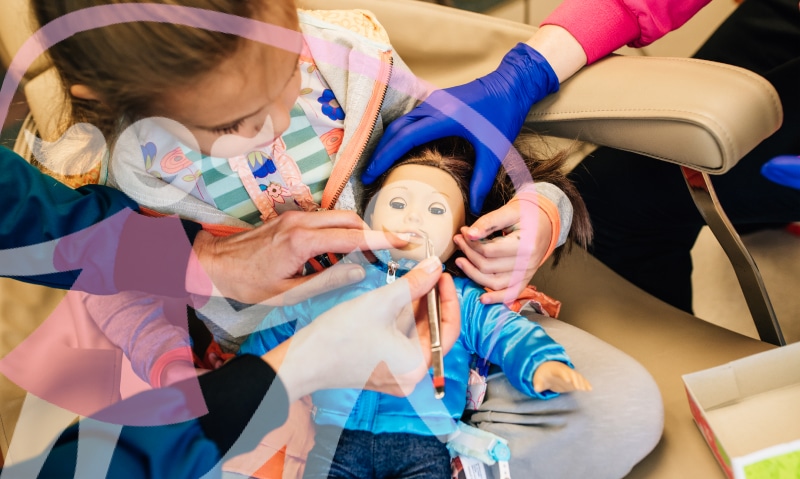 a young patient practices being a dentist on a doll